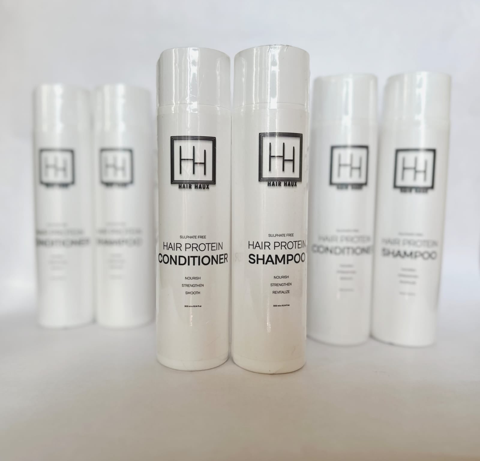 Hair care essentials displayed on a vanity, including protein shampoo, conditioner, and Hair Haux 100% human Remy hair extensions.
